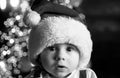 Cute baby face in Santa hat near Christmas tree. Happy Childhood, child 1 year old. New year kids. Royalty Free Stock Photo