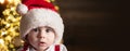 Cute baby face in Santa hat near Christmas tree. Happy Childhood, child 1 year old. New year kids. Horizontal banner for Royalty Free Stock Photo