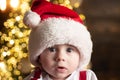 Cute baby face in Santa hat near Christmas tree. Happy Childhood, child 1 year old. New year kids. Royalty Free Stock Photo