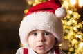 Cute baby face in Santa hat near Christmas tree. Happy Childhood, child 1 year old. New year kids. Royalty Free Stock Photo