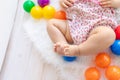 Cute baby feet on a white Mat among bright toys