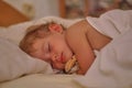 The cute baby fell asleep. A small Caucasian toddler sleeps in white sheets. Toddler is a girl with closed eyes and Royalty Free Stock Photo