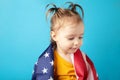 Cute baby girl with American flag on blue background. Little patriot. Happy Independence Day