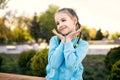 Cute baby girl in a blue jacket with pigtails posing sitting on a bench at sunset Royalty Free Stock Photo