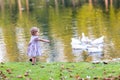 Cute baby girl chasing wild geese in an autumn park