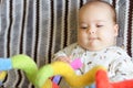 Cute baby girl on colorful playmat and gym, playing with hanging rattle toys. Kids activity and play center for early infant