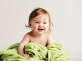 Cute baby girl with cozy green blanket smiling.