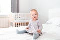 Cute baby girl in a dress and tights sitting on the bed. in the background, the interior of the bedroom. The concept of a happy Royalty Free Stock Photo