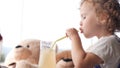 Cute baby girl drinks lemonade with in a cafe with many teddy bears