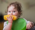 Cute baby girl eating corn