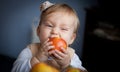 Cute baby girl eating a juicy red apple