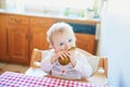 Cute baby girl eating pear in the kitchen Royalty Free Stock Photo