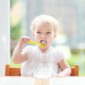 Cute baby girl eating yogurt from spoon Royalty Free Stock Photo