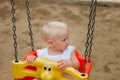 Cute blond baby girl sitting in a swing Royalty Free Stock Photo