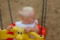 Cute blond baby girl sitting in a swing Royalty Free Stock Photo