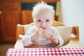 Cute baby girl feeding herself with finger food in the kitchen Royalty Free Stock Photo