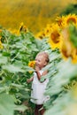 Cute baby girl in field with sunflowers. little girl is holding sunflower in her hand. The concept of summer holiday. baby`s day.