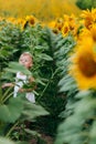 Cute baby girl in field with sunflowers. little girl is holding sunflower in her hand. The concept of summer holiday. baby`s day.