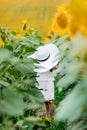 Cute baby girl in field with sunflowers. little girl plays with mom`s white hat. selective focus