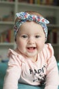 Cute baby girl with hairband ribbon, smiling, laughing. Adorable child having fun at home, happiness concept