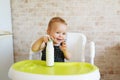 Cute baby girl holding nursing bottle and drinking formula milk. First food for babies. New born child, sitting in chair of Royalty Free Stock Photo