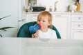 Cute baby girl in home clothes drinking water from bottle in kitchen at home Royalty Free Stock Photo