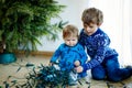 Cute baby girl and kid boy taking down holiday decorations from Christmas tree. children, siblings, brother and sister