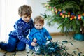 Cute baby girl and kid boy taking down holiday decorations from Christmas tree. children, siblings, brother and sister Royalty Free Stock Photo