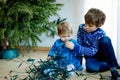 Cute baby girl and kid boy taking down holiday decorations from Christmas tree. children, siblings, brother and sister Royalty Free Stock Photo