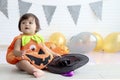 Cute baby girl kid dressing up in orange fancy Halloween pumpkin costume, cheerful little cute child holding black witch hat ready Royalty Free Stock Photo