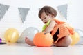 Cute baby girl kid dressing up in orange fancy Halloween pumpkin costume, cheerful little cute child holding orange pumpkin to Royalty Free Stock Photo