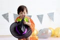 Cute baby girl kid dressing up in orange fancy Halloween pumpkin costume, cheerful little cute child holding black witch hat ready Royalty Free Stock Photo