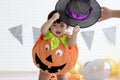 Cute baby girl kid dressing up in orange fancy Halloween pumpkin costume, cheerful little cute child holding black witch hat ready Royalty Free Stock Photo