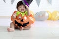 Cute baby girl kid dressing up in orange fancy Halloween pumpkin costume, cheerful little cute child holding black witch hat ready Royalty Free Stock Photo