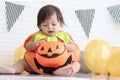 Cute baby girl kid dressing up in orange fancy Halloween pumpkin costume, cheerful little cute child holding orange pumpkin to Royalty Free Stock Photo