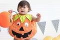 Cute baby girl kid dressing up in orange fancy Halloween pumpkin costume, cheerful little cute child holding orange pumpkin to Royalty Free Stock Photo