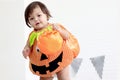 Cute baby girl kid dressing up in orange fancy Halloween pumpkin costume, cheerful little cute child holding orange pumpkin to Royalty Free Stock Photo