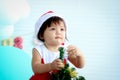 Cute baby girl kid in Santa Claus red costume trying to decorate Christmas tree in white living room, beautiful little child Royalty Free Stock Photo