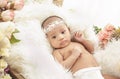 Cute baby girl lying on fur blanket with flowers around Royalty Free Stock Photo