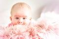 Cute baby girl lying on furry blanket on the bed at home and watching curiously Royalty Free Stock Photo