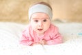 Cute baby girl lying on furry blanket on the bed at home and watching curiously Royalty Free Stock Photo