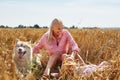 Cute baby girl with mom and dog on wheat field. Happy young family enjoy time together at the nature. Mom, little baby Royalty Free Stock Photo