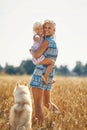 Cute baby girl with mom and dog on wheat field. Happy young family enjoy time together at the nature. Mom, little baby Royalty Free Stock Photo