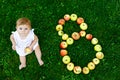 Cute baby girl with number 8 as eight months made with ripe apples on a farm in early autumn. Little baby girl playing Royalty Free Stock Photo