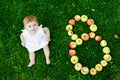 Cute baby girl with number 8 as eight months made with ripe apples on a farm in early autumn. Little baby girl playing Royalty Free Stock Photo