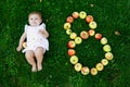 Cute baby girl with number 8 as eight months made with ripe apples on a farm in early autumn. Little baby girl playing Royalty Free Stock Photo