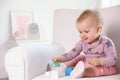 Cute baby girl playing with building blocks in armchair at home Royalty Free Stock Photo