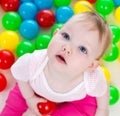 Cute baby girl playing among colorful balls