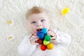 Cute baby girl playing with colorful wooden rattle toy, nursing bottle and dummy Royalty Free Stock Photo