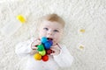 Cute baby girl playing with colorful wooden rattle toy, nursing bottle and dummy Royalty Free Stock Photo